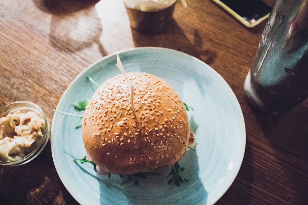 Burger with a sesame bun on a light blue plate. Original public domain image from Wikimedia Commons