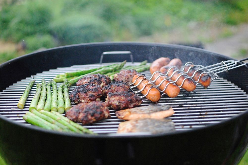 Hot grill barbecuing asparagus, hot dogs, and meat. Original public domain image from Wikimedia Commons