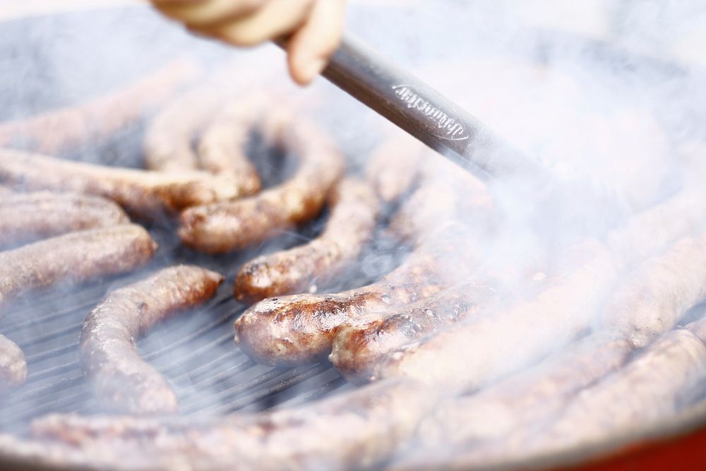 Grilling smokey sausages and brats on a grill. Original public domain image from Wikimedia Commons