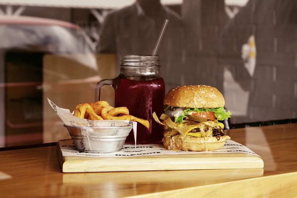 Cheeseburger, red juice drink, and a basket of fries at a restaurant. Original public domain image from Wikimedia Commons