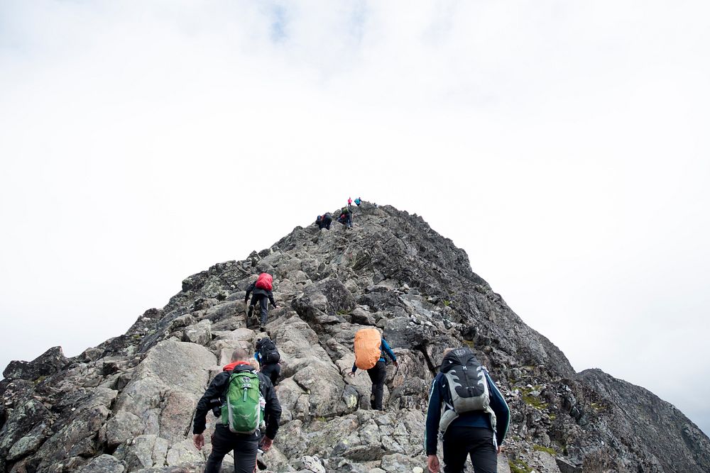 Hikers with backpacks summiting peaks of mountain. Original public domain image from Wikimedia Commons