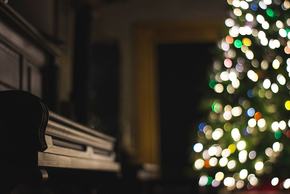 A dim shot of a piano next to a Christmas tree with bokeh effect. Original public domain image from Wikimedia Commons