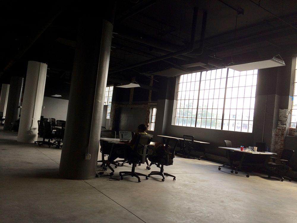 A lone employee working in a large loft office. Original public domain image from Wikimedia Commons