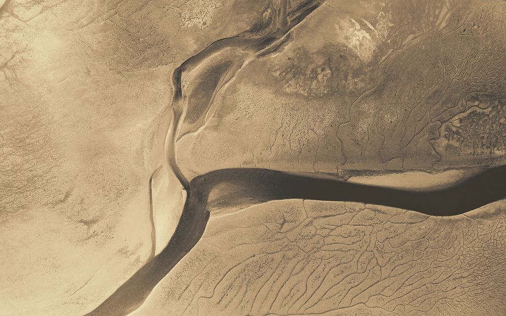 Drone shot of a river flowing through an arid plain. Original public domain image from Wikimedia Commons