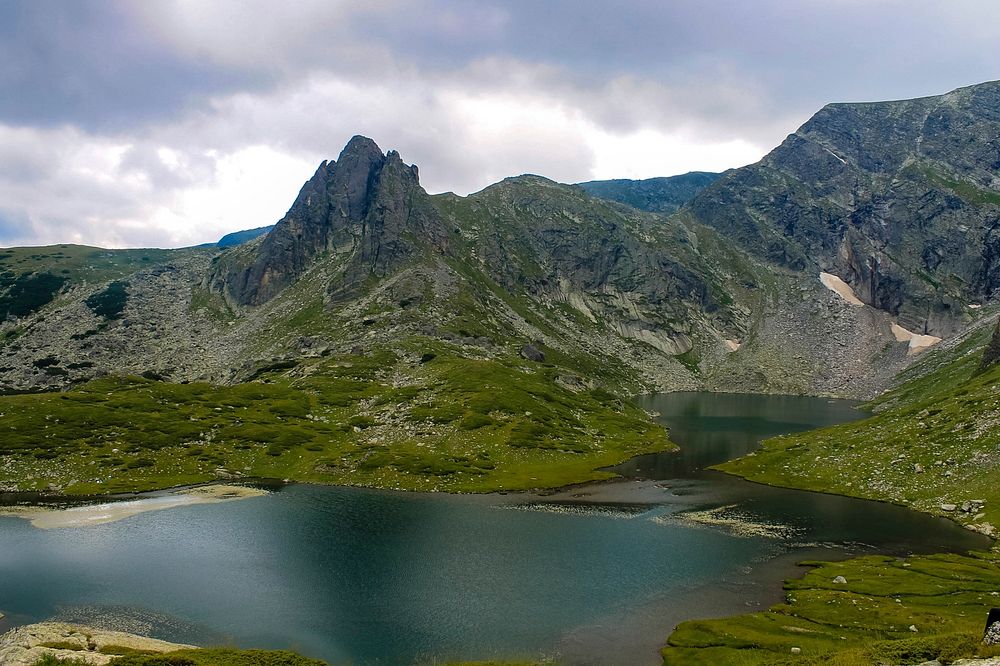 A dark turquoise lake in the middle of a green mountain valley. Original public domain image from Wikimedia Commons