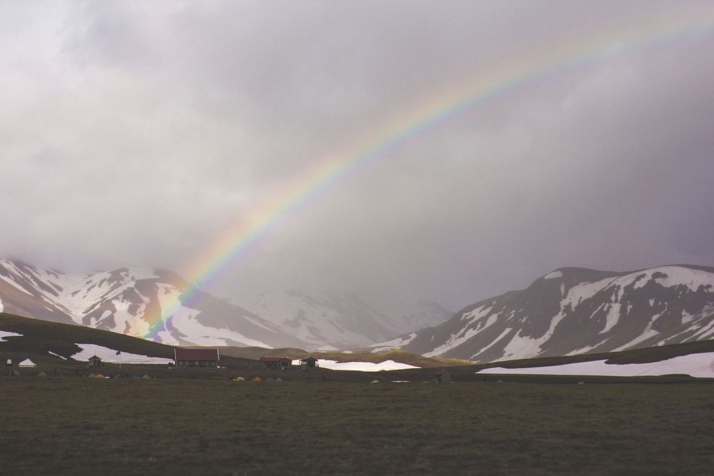 A landscape of rainbow over a field with a view of mountains covered in snow. Original public domain image from Wikimedia…
