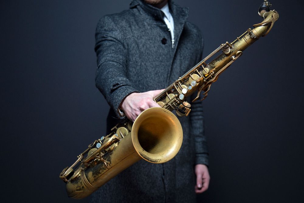 A man in suit holding a saxophone. Original public domain image from Wikimedia Commons