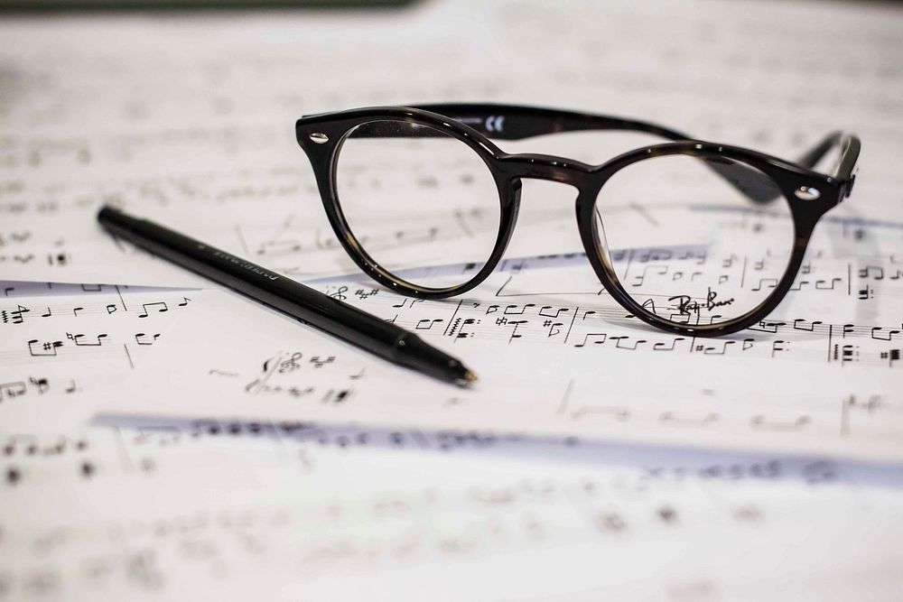 A pen and a pair of glasses on music sheets. Original public domain image from Wikimedia Commons