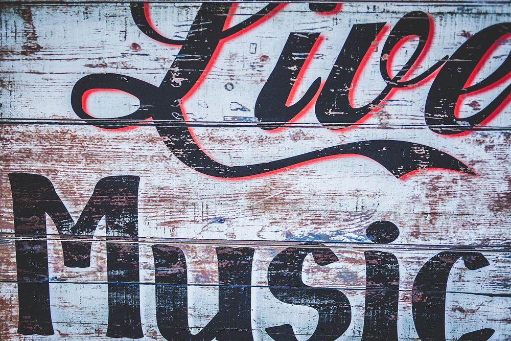 A graffiti sign on a worn-out wooden wall reads “Live Music”. Original public domain image from Wikimedia Commons
