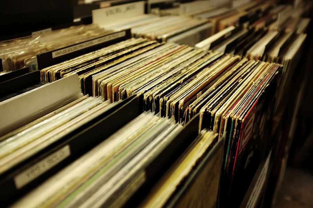 Old vinyl records lined up on the shelf of a music store. Original public domain image from Wikimedia Commons