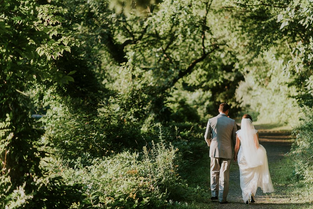 A bridal couple walking on a dirt path lined with trees. Original public domain image from Wikimedia Commons