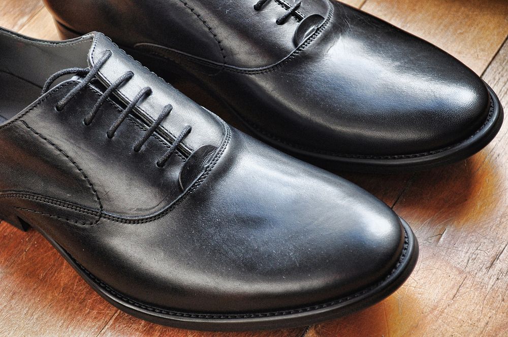 Black oxford shoes on wooden background. Original public domain image from Wikimedia Commons
