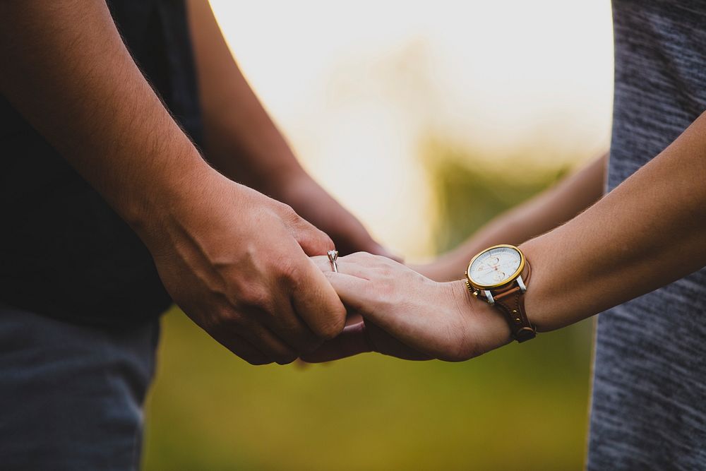 Close-up outdoors of man holding the hands of woman wearing a watch. Original public domain image from Wikimedia Commons