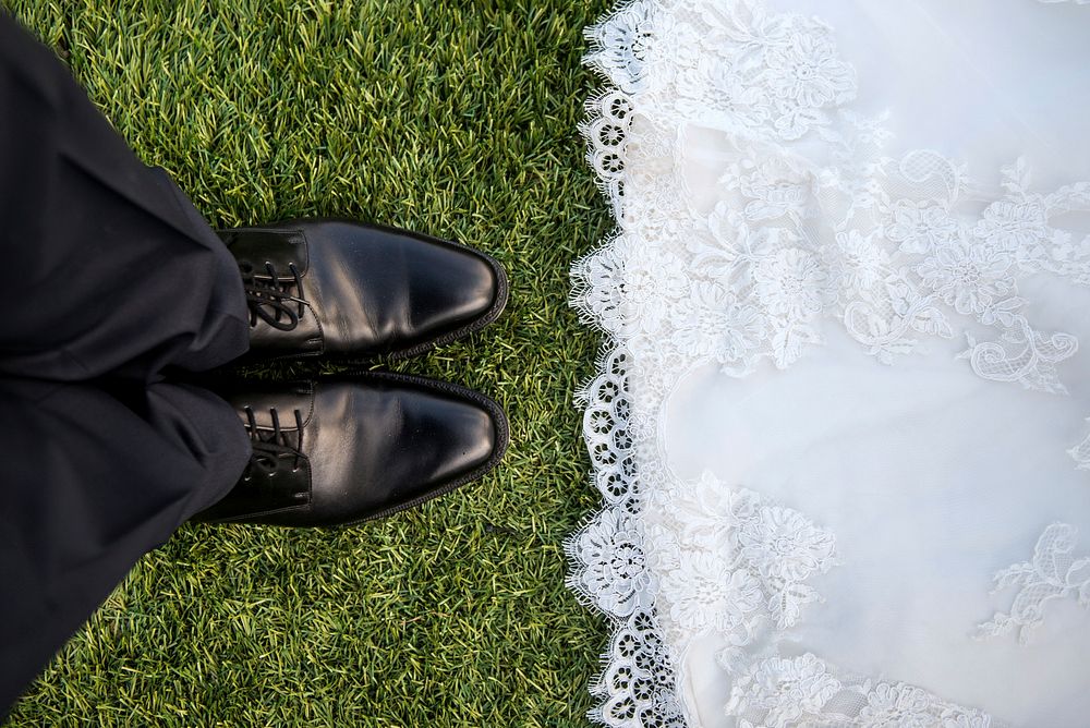 Bride wearing lace dress faces groom wearing black pants and shoes. Original public domain image from Wikimedia Commons