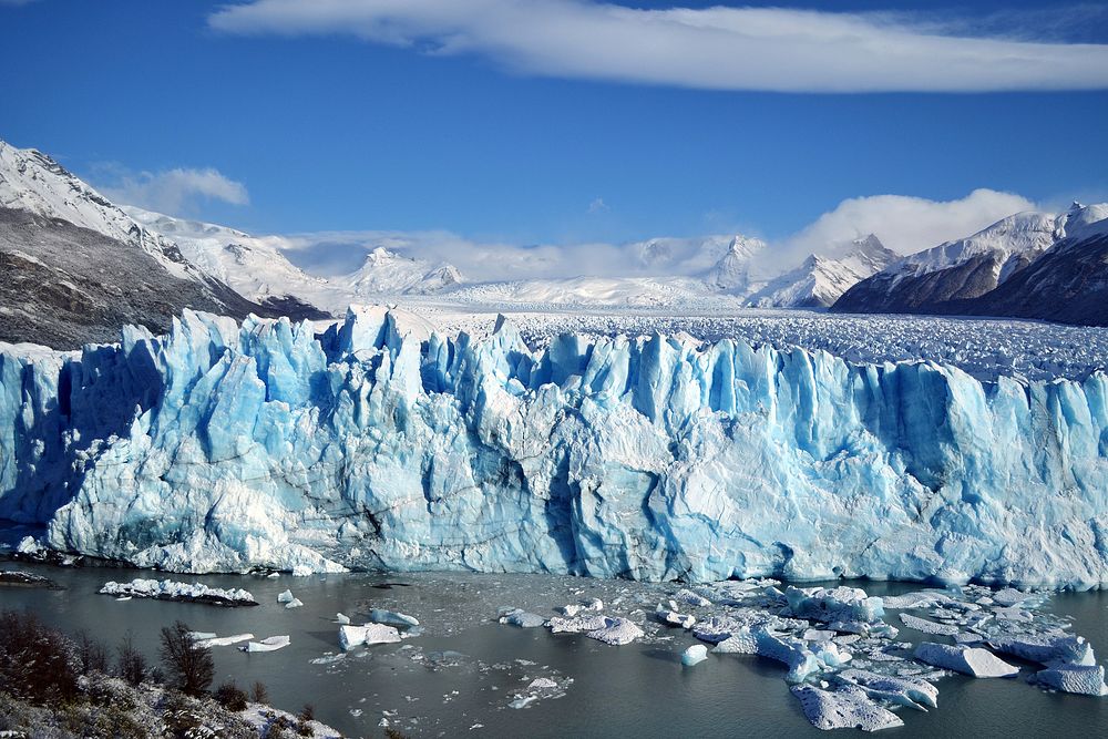 A river flowing along an ice blue glacier in the mountains. Original public domain image from Wikimedia Commons
