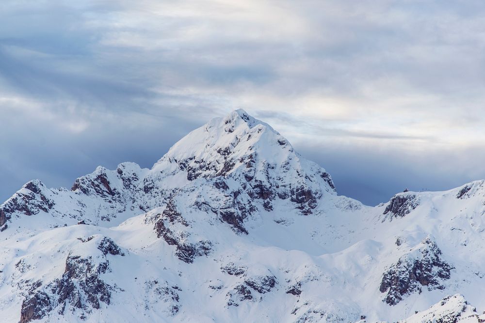 A rugged snow-capped mountain summit against an overcast sky. Original public domain image from Wikimedia Commons