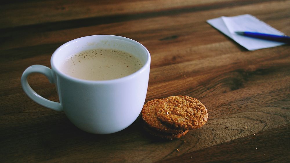 A mug of coffee with a biscuit sitting next to it. Original public domain image from Wikimedia Commons