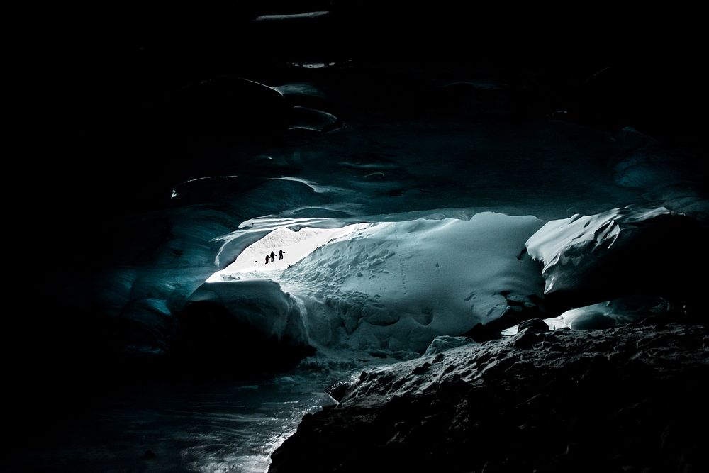 People in the opening of a cave filled with ice and snow. Original public domain image from Wikimedia Commons