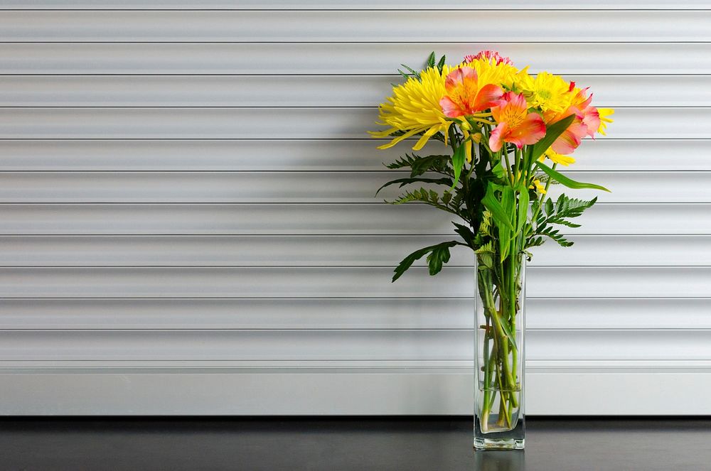 Glass vase holding yellow and red flowers. Original public domain image from Wikimedia Commons