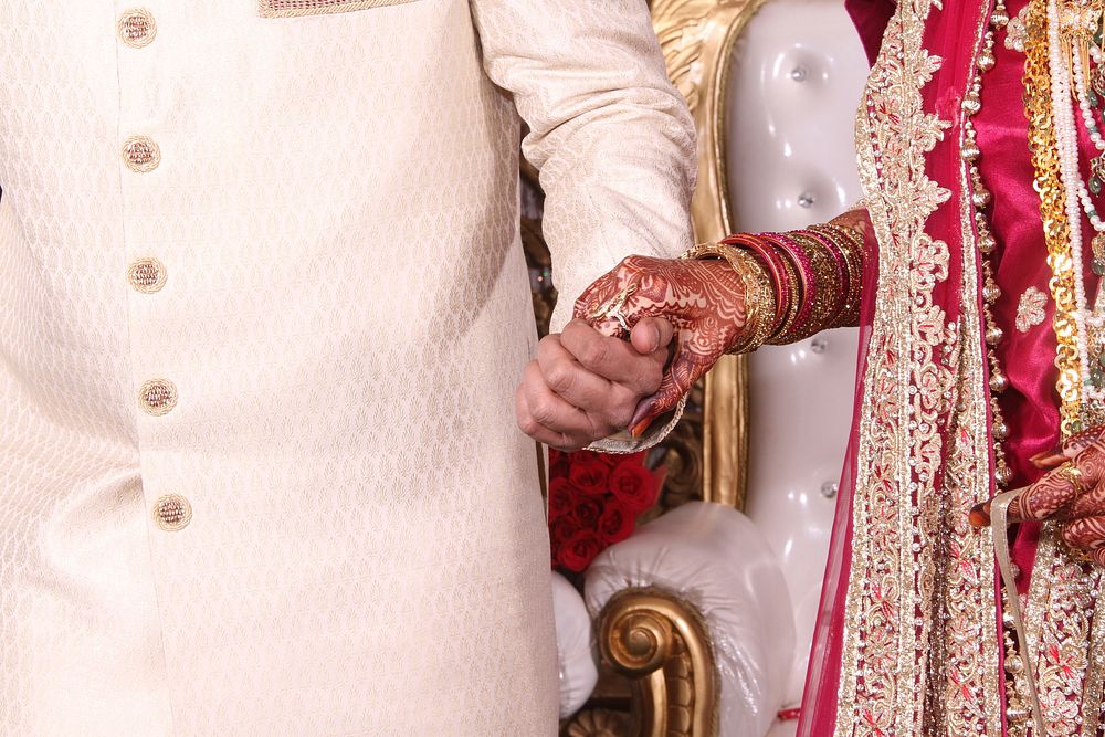Bride in red and gold dress holds hands with groom in India. Original public domain image from Wikimedia Commons