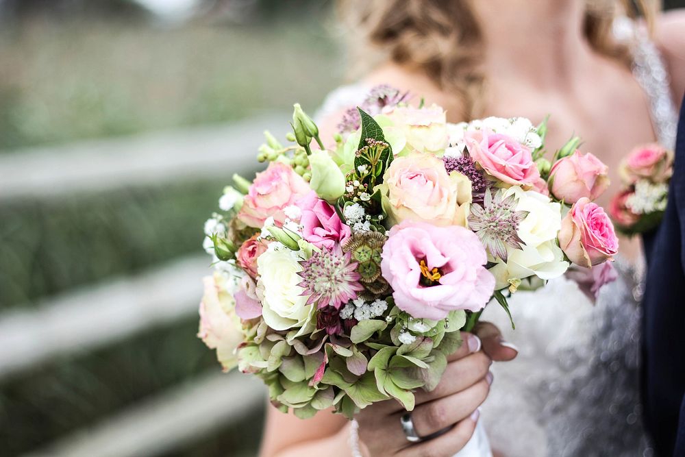 A bride holding a bouquet with pink roses and other delicate flowers. Original public domain image from Wikimedia Commons