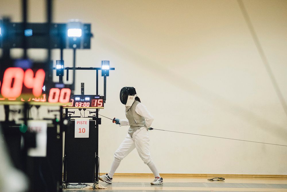 A person walking with a cable and fencing sword in a timed match. Original public domain image from Wikimedia Commons