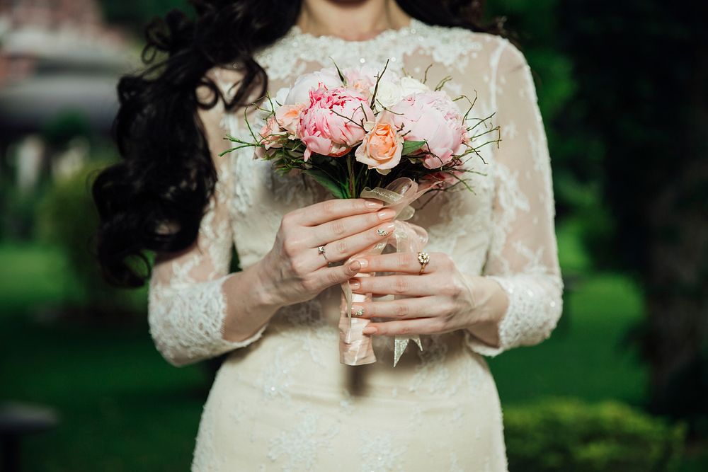 A woman in a bridal dress with a small bouquet of peonies and roses. Original public domain image from Wikimedia Commons