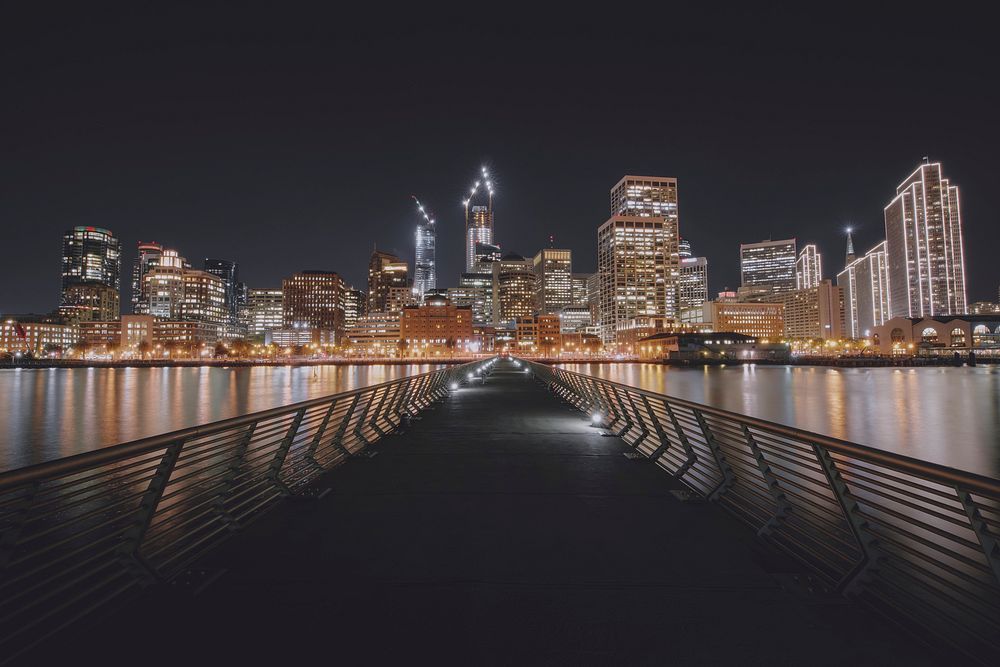 A look down Pier 14 with cityscape lighting reflections in the surrounding water. Original public domain image from…