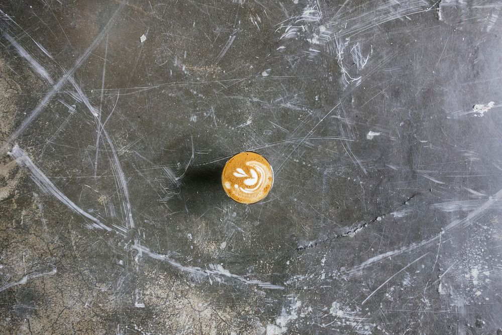 Cappuccino with heart foam art on a scratched but smooth concrete table. Original public domain image from Wikimedia Commons