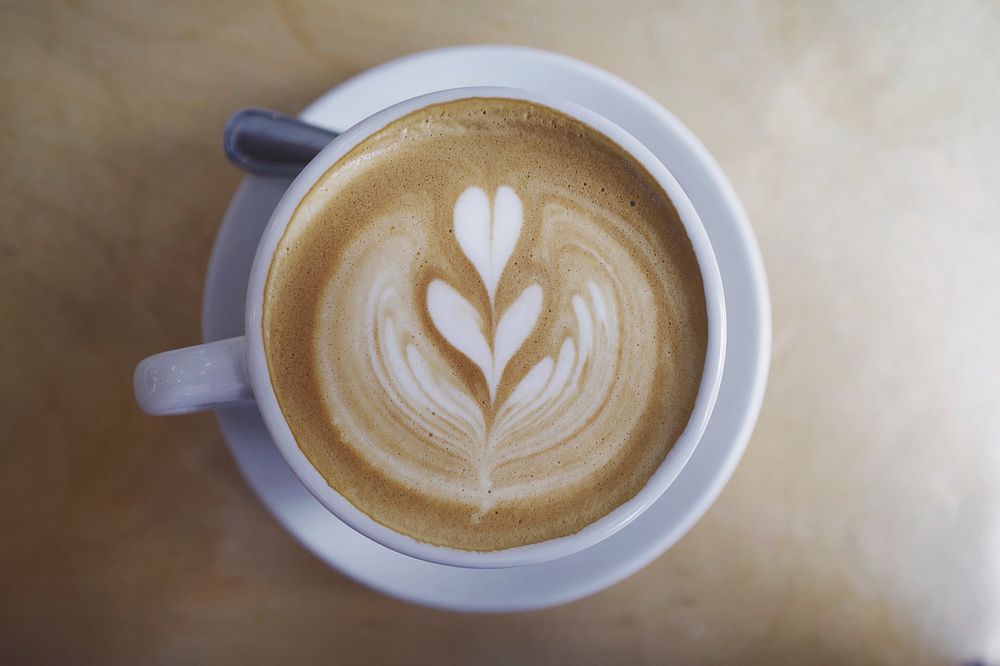 A cup of coffee with a leaf painted in the milk at Two Hands Cafe. Original public domain image from Wikimedia Commons