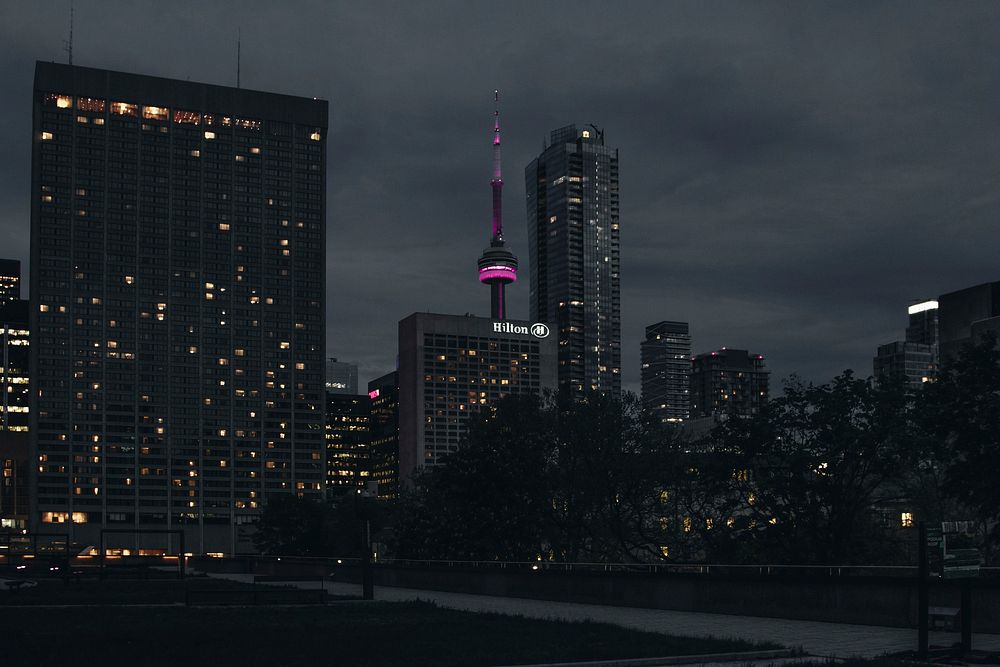 A dim cityscape of Toronto with the CN tower lit up in purple. Original public domain image from Wikimedia Commons