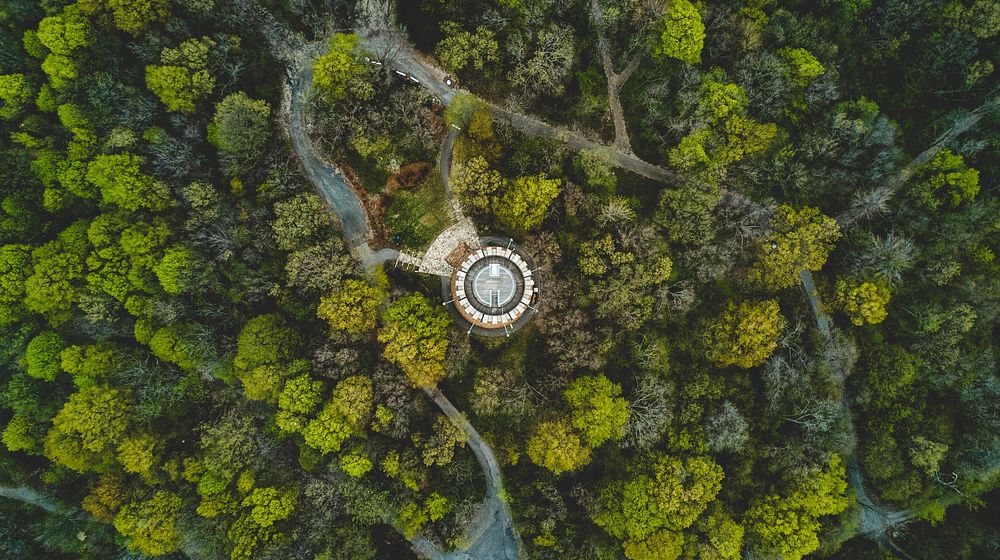 A drone shot of a round building in a wooded area with narrow footpaths. Original public domain image from Wikimedia Commons
