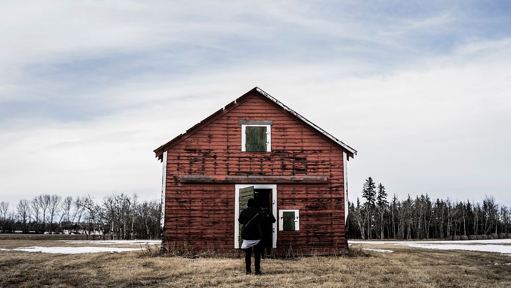 Two people in front of a barn on a winter's day. Original public domain image from Wikimedia Commons