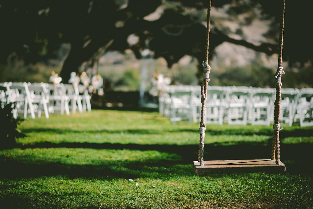 Wooden swing behind wedding ceremony chairs and grass. Original public domain image from Wikimedia Commons