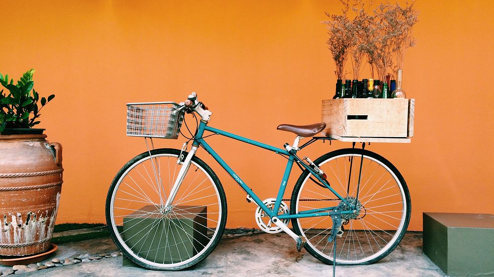 A bicycle with a crate of wine on its carrier against an orange wall. Original public domain image from Wikimedia Commons