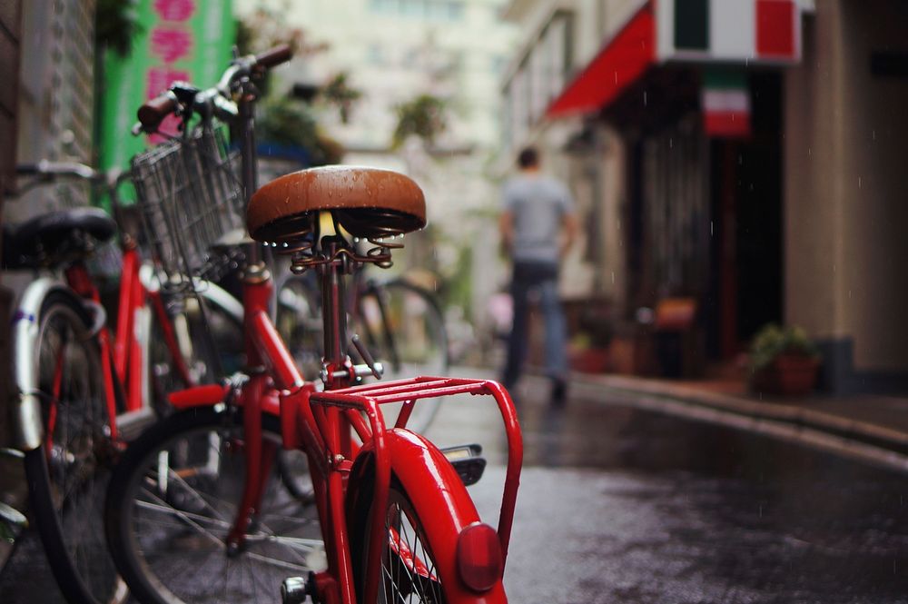Red vintage bicycle parked on a rainy city street. Original public domain image from Wikimedia Commons