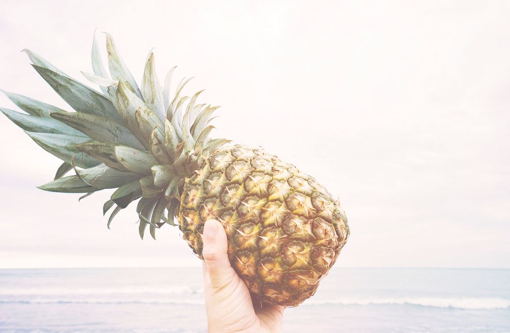 Holding a pineapple at the beach.. Original public domain image from Wikimedia Commons