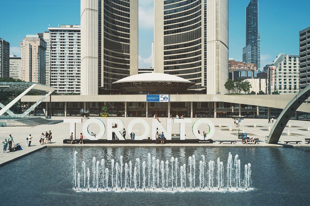 Large letters spell out "Toronto" next to a fountain in an urban plaza. Original public domain image from Wikimedia Commons