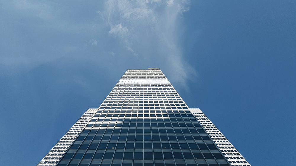 The white exterior of a tall skyscraper under a blue sky. Original public domain image from Wikimedia Commons