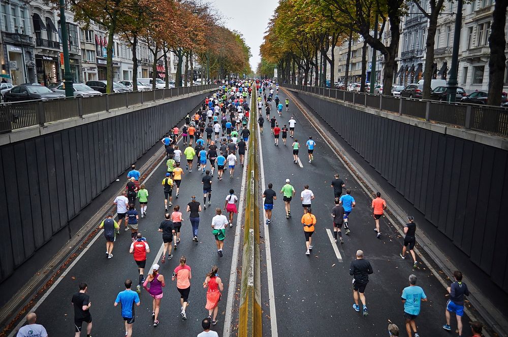 A large group of people running in a marathon in the middle of a street in Brussels. Original public domain image from…