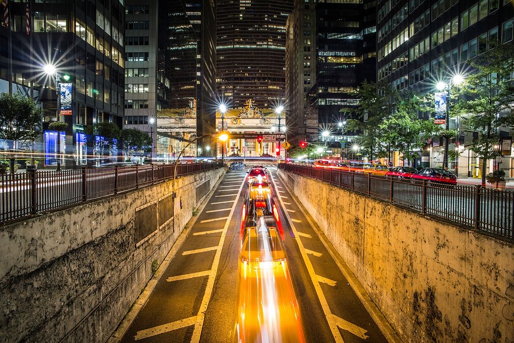 Time lapse shot of New York city center street at night-time surrounded by skyscrapers. Original public domain image from…