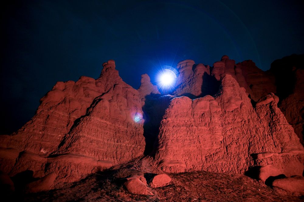 Bright blue light shines over red rocks of Goblin Valley State Park at night. Original public domain image from Wikimedia…