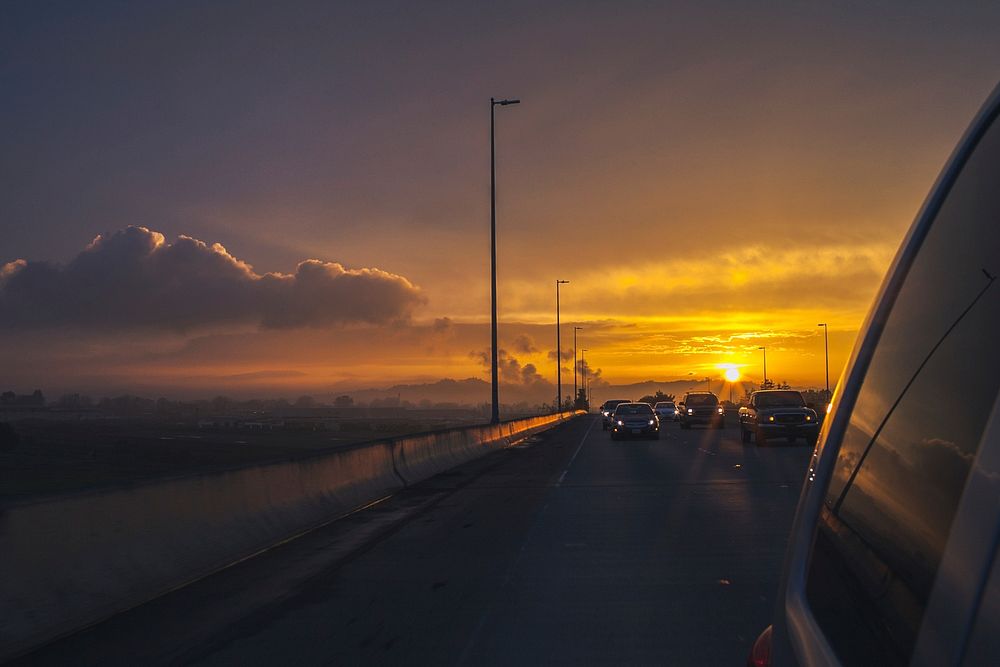 Sun sets behind a car in freeway traffic. Original public domain image from Wikimedia Commons