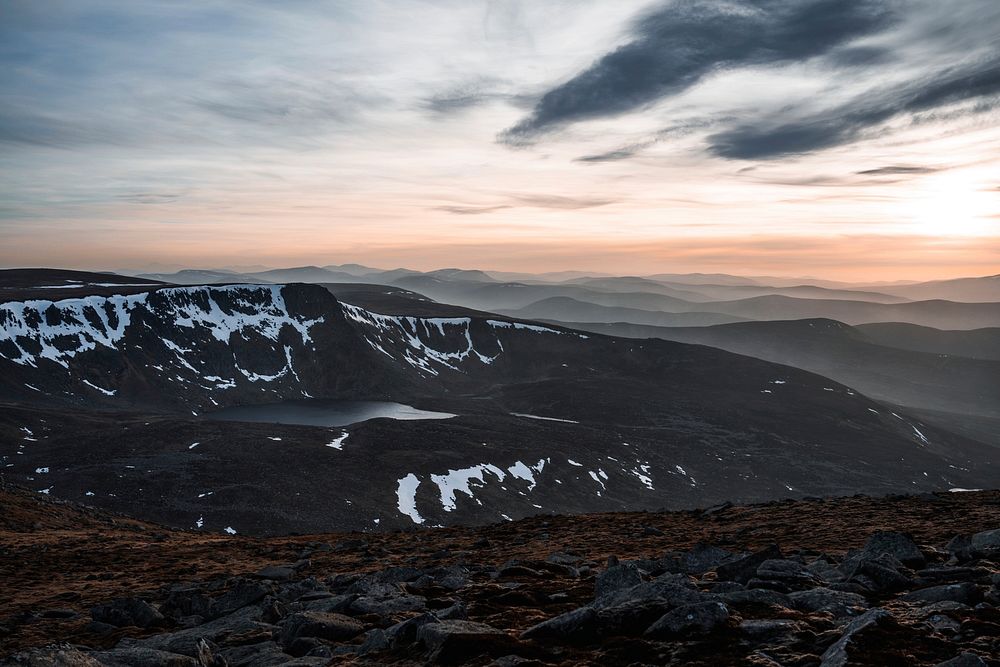Clouds swept across sky with sunset and snowy mountains in distance at Lochnagar. Original public domain image from…