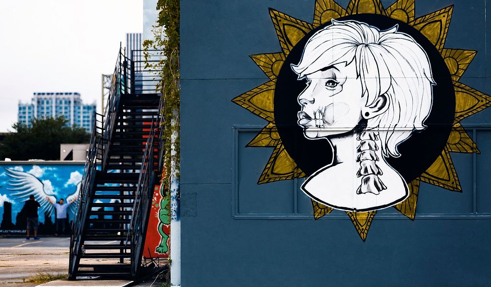 Urban stairwell and white graffiti of woman's face and head on urban building in Houston. Original public domain image from…