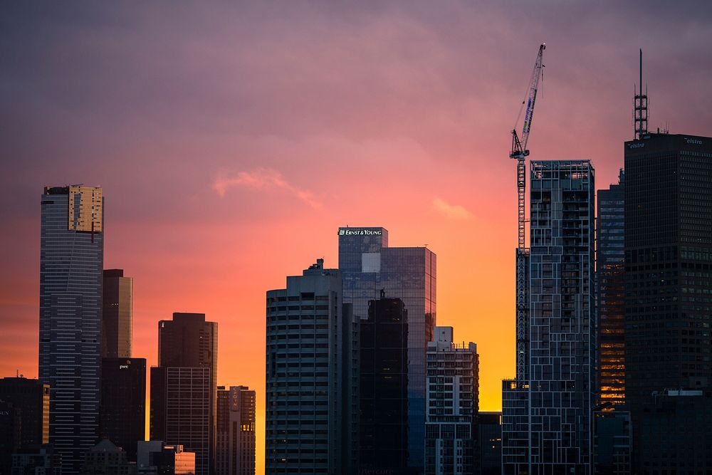 A pink and orange sunset behind the skyscrapers of Melbourne. Original public domain image from Wikimedia Commons