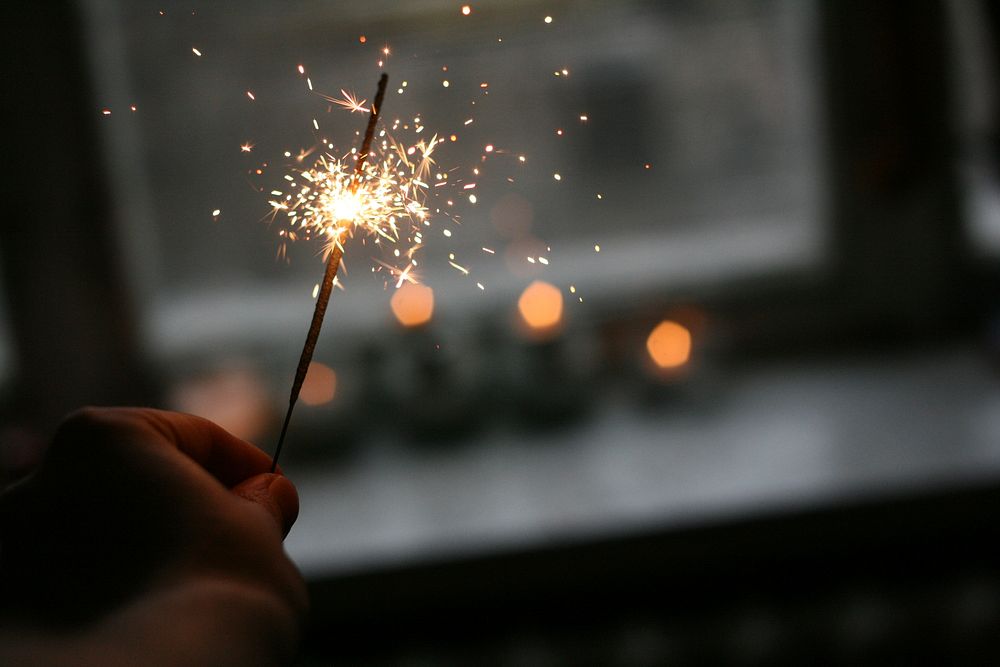 A person holding a sparkler near a window. Original public domain image from Wikimedia Commons