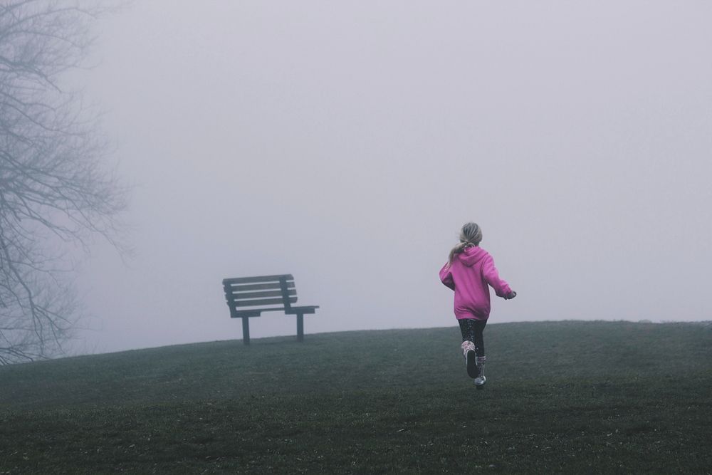Girl runs towards a bench in a cold and foggy park. Original public domain image from Wikimedia Commons
