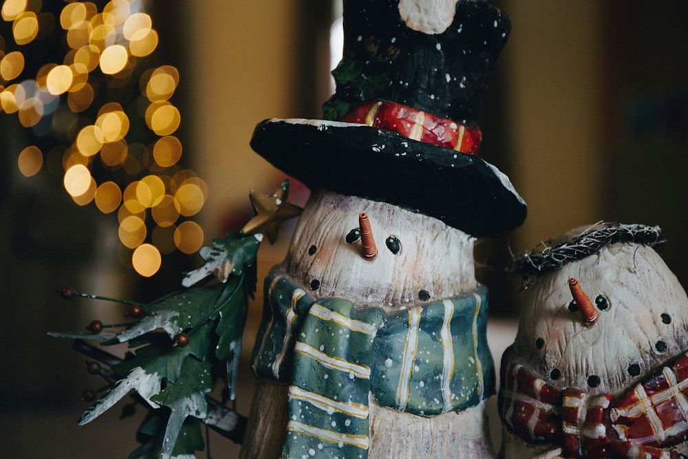 Two snowmen in focus in front of bokeh Christmas decorations. Original public domain image from Wikimedia Commons