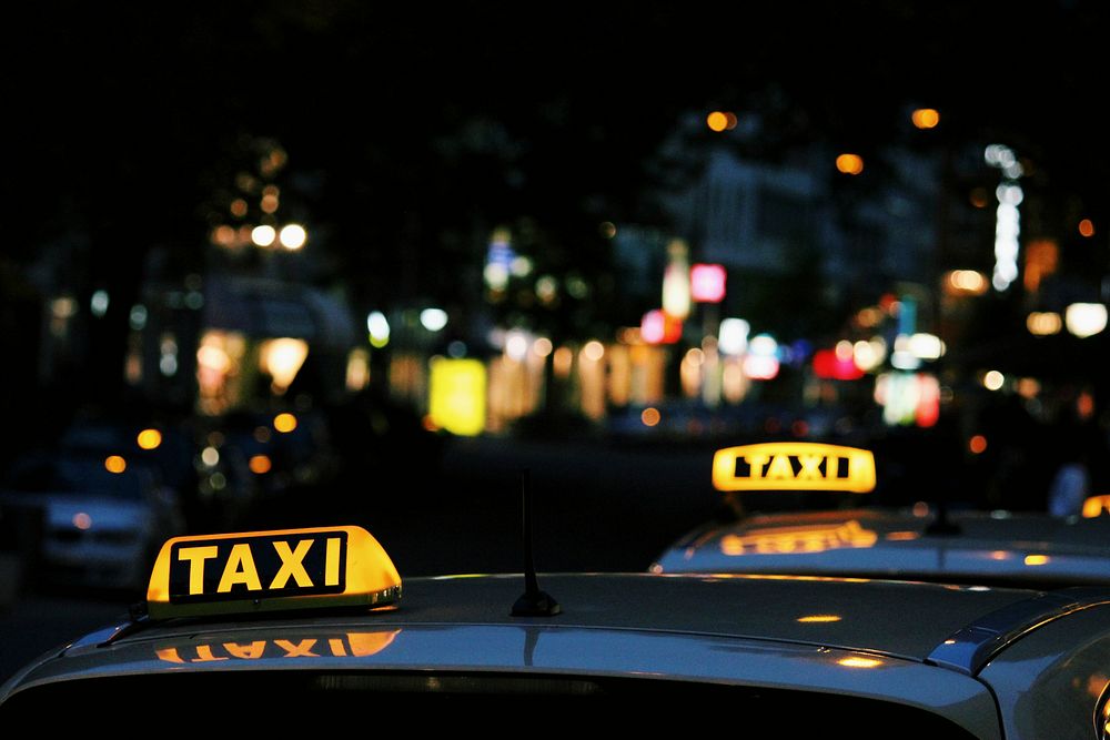 Taxis at night in Budapest with the city in the background. Original public domain image from Wikimedia Commons